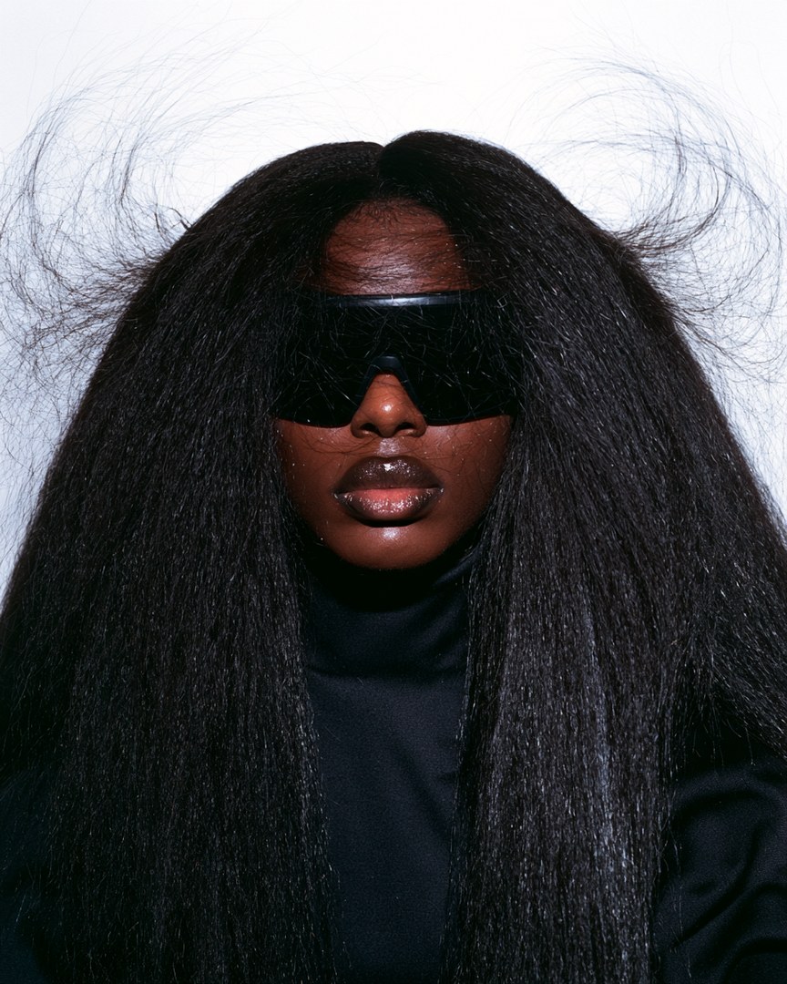 Editorial portrait of a model with long, textured hair and dark protective eyewear, used to illustrate the conditions GF-01 is being developed for.